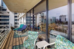 Un balcon doté de chaises longues et d’une rambarde en verre, offrant une vue sur le paysage urbain.