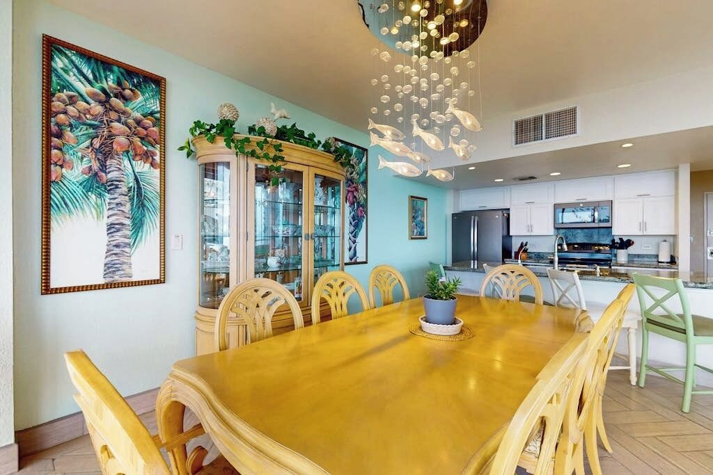 A dining area with a wooden table and chairs, a decorative cabinet, and a large framed picture on the wall.