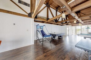 A spacious room with a pool table, a blue folding chair, and a ping pong table. - Gulf Point Condominiums #3308 (South Padre Island)