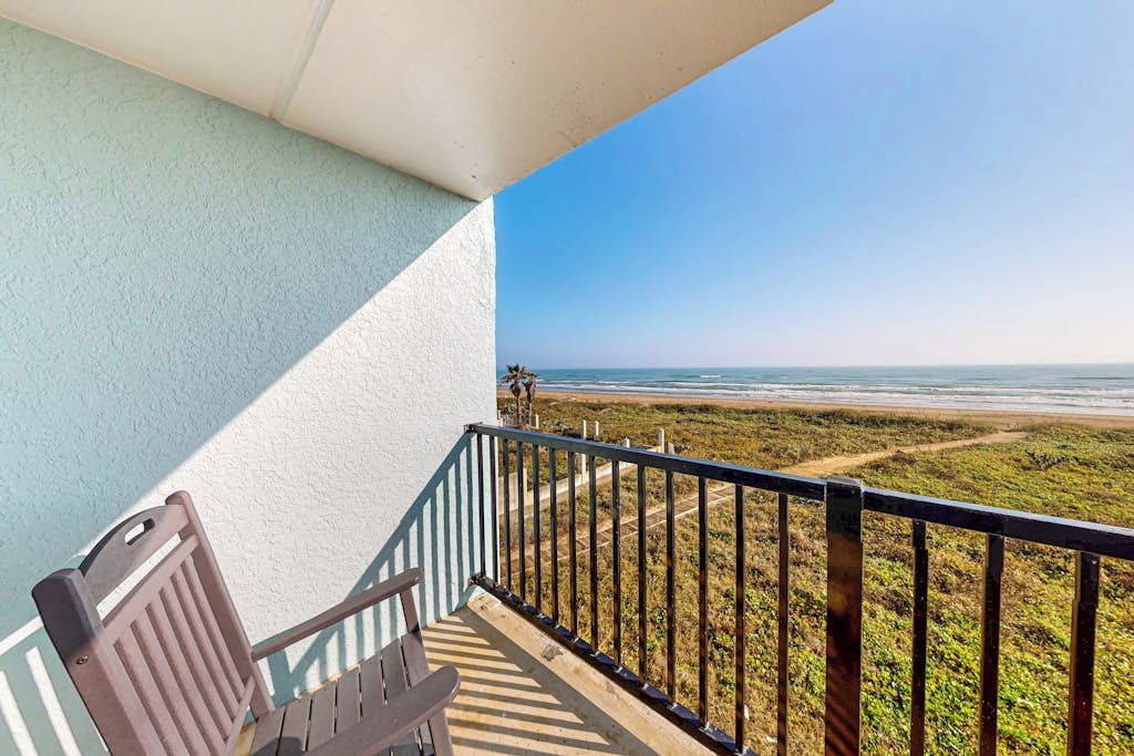 Ein Balkon mit Blick auf den Strand, ein Stuhl und ein Geländer.