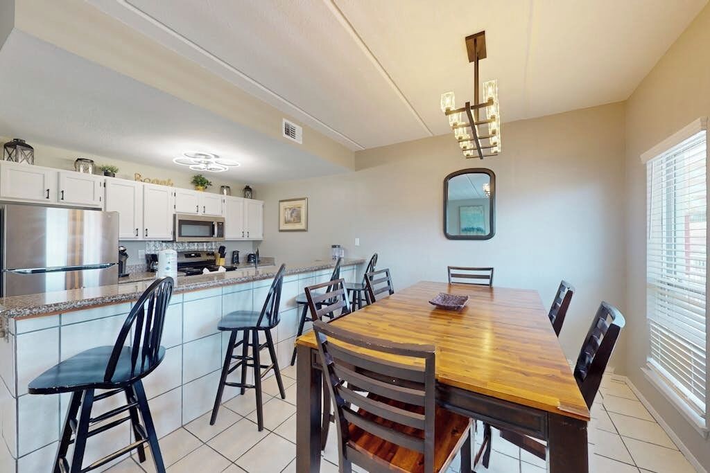 A modern kitchen with a dining area, featuring a wooden table, chairs, and a built-in oven.