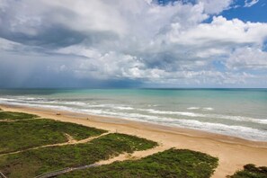 Ein Strand mit freiem Blick auf den Ozean und einem bewölkten Himmel.