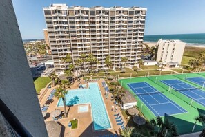 Ein Hotel mit mehreren Etagen, einem Schwimmbad und Tennisplätzen.