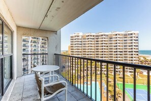 A balcony with a table and chairs, overlooking a high-rise building and a beach. - Saida Towers IV #4906 (South Padre Island)