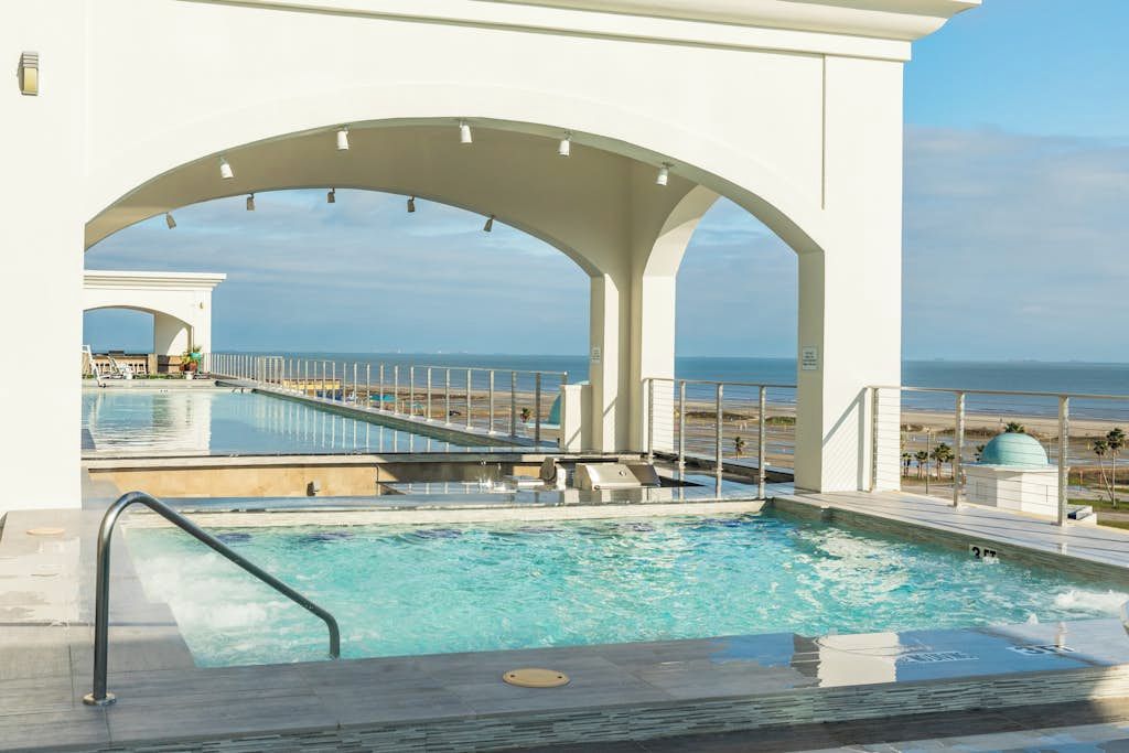 Área da piscina com vista para o oceano, um deck coberto e um espaço para relaxamento.