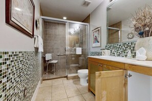 Un bagno con doccia vetrata, un water e un lavandino con uno specchio sopra.