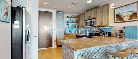 A modern kitchen with a central island, bar stools, and a dining area.