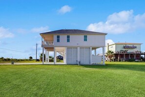 A two-story house with a covered porch and a garage. - Wishing Star - Hot Tub, Gulf Views, Steps to Sand (Galveston)