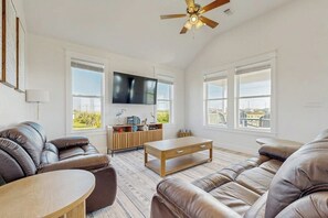 Een woonkamer met leren banken, een houten salontafel en een flatscreen televisie aan de muur.