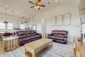 A spacious living area with leather sofas, a wooden coffee table, and a ceiling fan. - Wishing Star - Hot Tub, Gulf Views, Steps to Sand (Galveston)