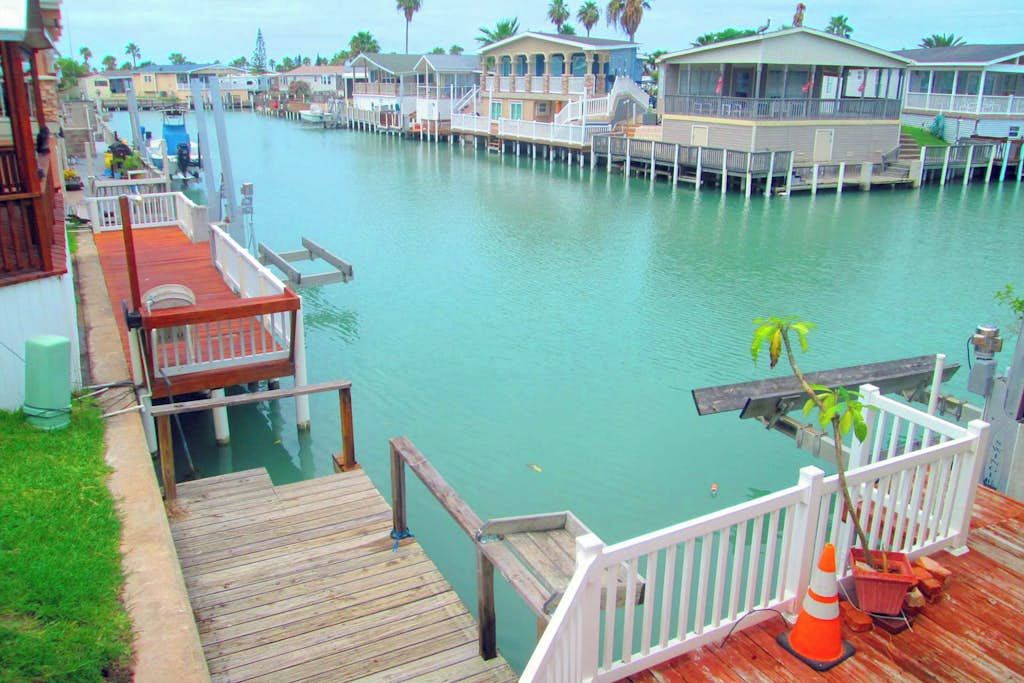 A waterfront property with multiple docked boats, a wooden deck, and a view of the water.