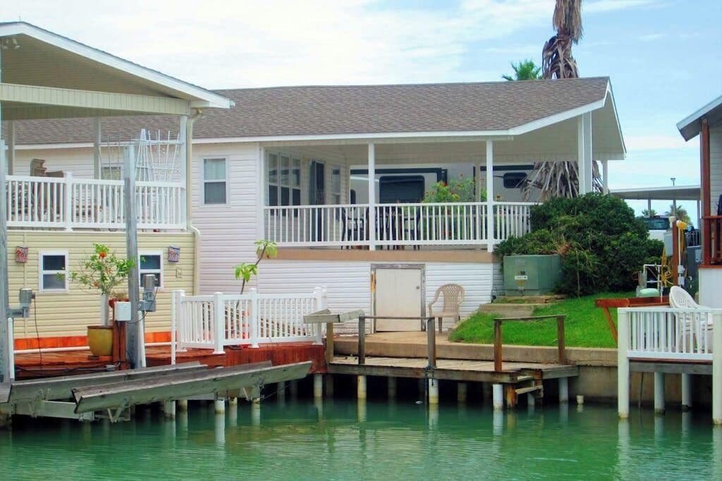 A waterfront property with a covered porch, dock, and a small boat.