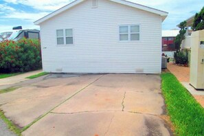 A single-story residential house with a garage, a driveway, and a small front yard. - Long Island Village 214 Bonnet (Port Isabel)