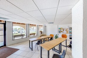 Espaço moderno e interno com uma grande janela, balcão de recepção e um mural de avisos.