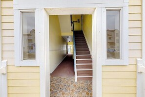 A hallway with a staircase leading to an upper floor, a window on the left, and a door on the right. - Beach Club 363 - Heated Pool & Hot Tub, Dogs OK (Corpus Christi)