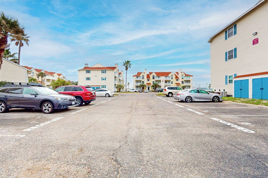 A parking lot with multiple cars and buildings in the background.