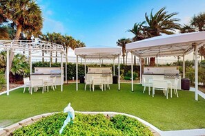 An outdoor patio with white canopies, barbecue grills, and seating areas. - The Blue Diamond - Lazy River Pool & Game Room (Galveston)