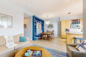 Ein modernes Wohnzimmer mit Sofa, Couchtisch und Essbereich mit einer Chandelier.