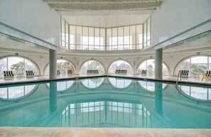 A large indoor swimming pool with multiple seating areas and large windows. - The Blue Diamond - Lazy River Pool & Game Room (Galveston)