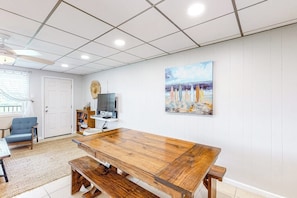 A spacious room with a large wooden table, a television, and a painting on the wall. - Unit 32, Island Retreat Resort (Port Aransas)