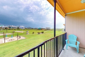 A balcony with a view of a grassy area and houses. - Unit 32, Island Retreat Resort (Port Aransas)