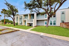 A multi-story residential building with balconies, a central staircase, and a well-maintained lawn. - Rockport Racquet & Yacht Club - Coastline Condo (Rockport)