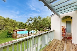 A wooden deck with a pool, surrounded by trees, and a covered patio area. - Rockport Racquet & Yacht Club - Coastline Condo (Rockport)