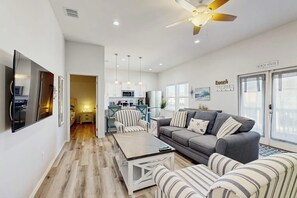 Ein modernes Wohnzimmer mit einem grauen Sofa, gestreiften Sesseln, einem Couchtisch und einem Deckenventilator.