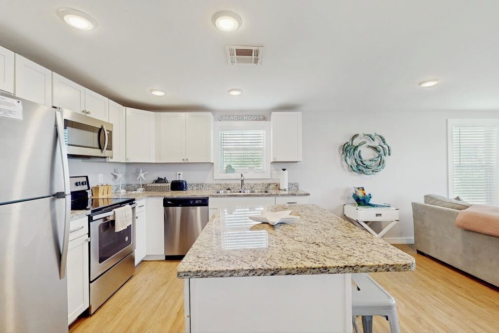 A modern kitchen with white cabinetry, stainless steel appliances, and a granite countertop.