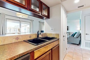 Une cuisine dotée d’un évier à deux bacs, de meubles de rangement en bois et d’une fenêtre avec des rideaux.