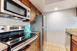A kitchen with stainless steel appliances, wooden cabinets, and a tiled backsplash. - Rockport Waterfront Getaway #608 (Rockport)