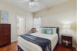 A bedroom with a bed, dresser, nightstand, and a ceiling fan. - Palm Bay 407 & 408 - Two Units, Pool, Sleeps 12 (Corpus Christi)