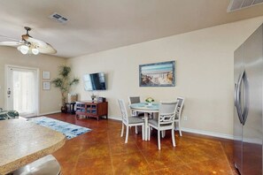 A kitchen with a granite countertop, a dining area with a table and chairs, a ceiling fan, a refrigerator, and a painting on the wall. - Palm Bay 407 & 408 - Two Units, Pool, Sleeps 12 (Corpus Christi)
