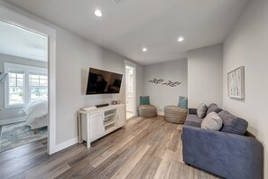 Ein modernes Wohnzimmer mit Flachbildfernseher an der Wand, einem grauen Sofa und einer weißen Unterhaltungseinheit.