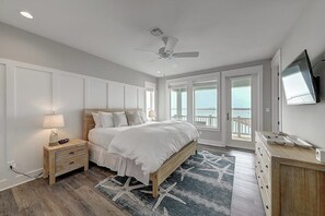 Ein Schlafzimmer mit Bett, Nachttisch, Schminktisch, Deckenventilator und Fernseher an der Wand.