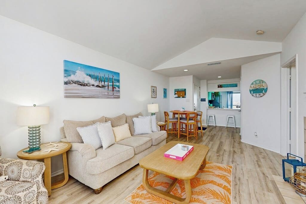 A living room with a sofa, coffee table, and a painting on the wall.