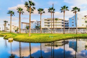 A waterfront property with a pool, palm trees, and a multi-story building with balconies.