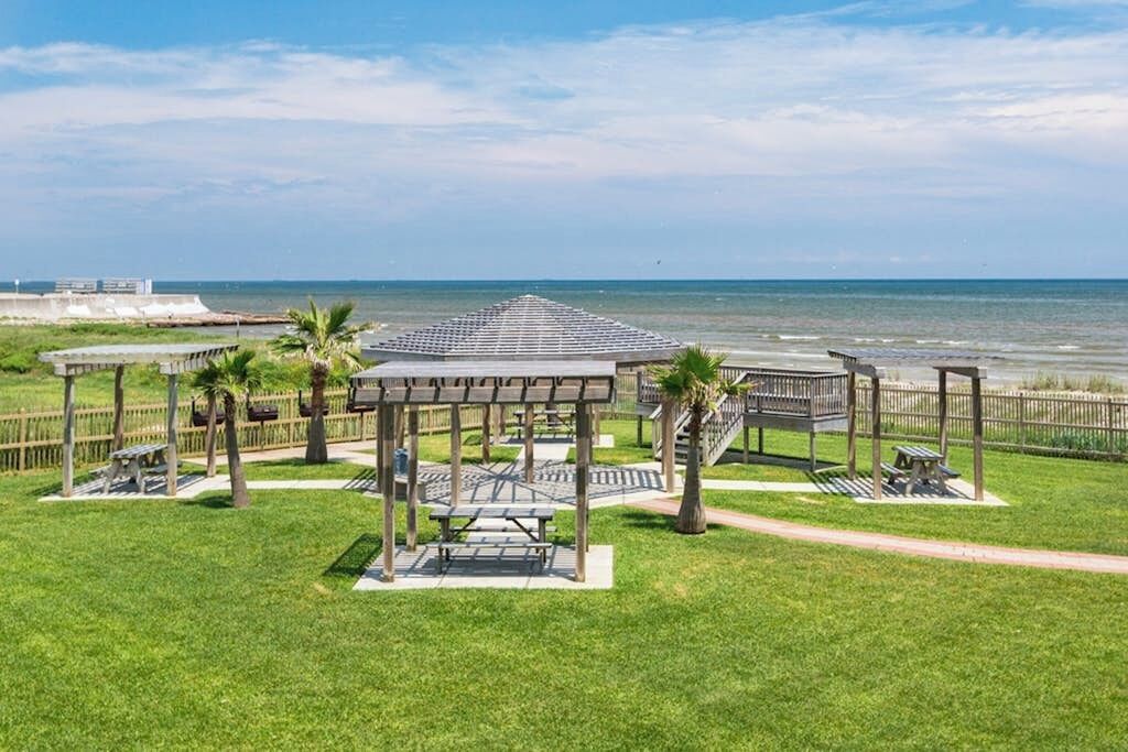 A beachside park with picnic tables, a gazebo, and a view of the ocean.