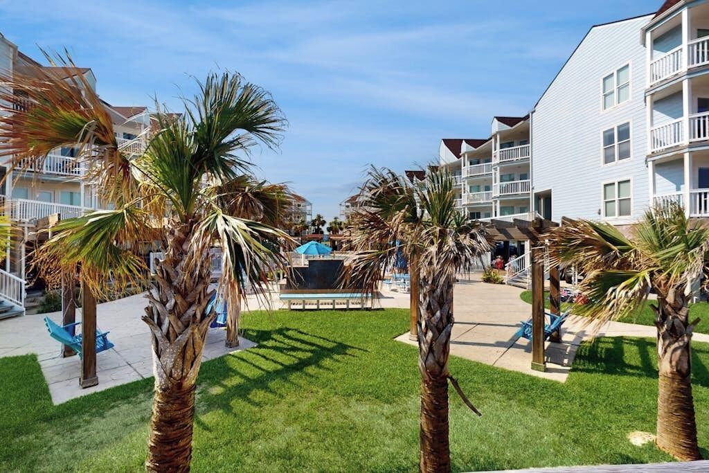 A resort with multiple-story buildings, palm trees, and a pool area.