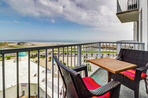 A balcony with wicker furniture and a view of the beach and cityscape. - Emerald by the Sea #806 (Galveston)