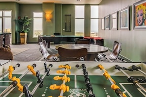 A room with a pool table, chairs, and a foosball table. - Emerald by the Sea #806 (Galveston)