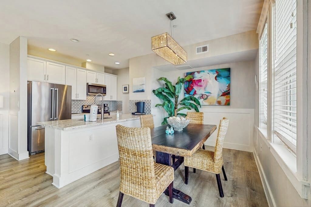 A modern kitchen with white cabinetry, stainless steel appliances, and a central island.