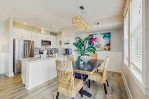 A modern kitchen with white cabinetry, stainless steel appliances, and a central island. - Pointe West Resort - Treasure on the Beach (Galveston)