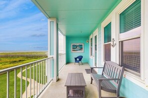 A balcony with a view of the beach, a table, and two chairs. - Pointe West Resort - Treasure on the Beach (Galveston)