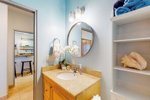 A bathroom with a sink, mirror, and shelves. - Seaside Oasis - Gulf Views, Pool & Fishing Pier (Galveston)