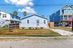 A residential property with a front porch, a small front yard, and a two-story house. - Out of the Blue - Fire Pit & Patio Near the Beach (Galveston)