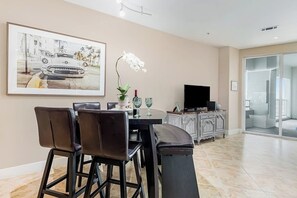 Ein Essbereich mit Tisch, Stühlen, einem Fernseher und einem Gemälde an der Wand.