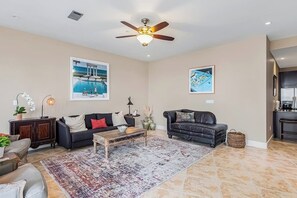 Ein geräumiges Wohnzimmer mit Deckenventilator, großem Teppich und zwei Sofas.