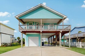 A two-story house with a balcony, a garage, and a covered front porch. - Blue Sunrise - Bay Views, Pool & Dog-Friendly (Galveston)