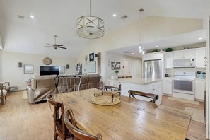 A spacious living area with a dining table, sofa, and kitchen in the background. - Blue Sunrise - Bay Views, Pool & Dog-Friendly (Galveston)